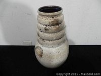 Front view of the large ceramic vase showing bulbous base and ribbed neck with white and brown glaze