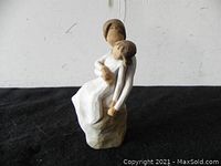Front view of the Willow Tree mother and daughter figurine showing the daughter resting on the mother's lap.
