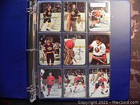 Binder page showing nine 1977 O-Pee-Chee hockey cards with player images and facsimile autographs.