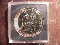 Reverse side of the 1988 Canadian silver 1 dollar coin showing two blacksmiths under the inscription 'LES FORGES DU SAINT-MAURICE IRONWORKS' in a protective case.