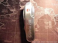 Closed view of Calvin Hill branded stainless steel multi-tool pocket knife on world map background