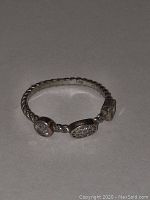 Close-up image of the 925 sterling silver ring with twisted band and three diamond stones.