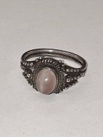 Oval cabochon quartz set in sterling silver ring with beaded and rope detailing on neutral background.