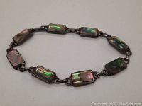 Bracelet laid on flat surface showing rectangular abalone shell inlays with iridescent colors in oxidized silver settings