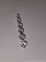 Sterling silver pendant with 6 clear round cubic zirconia stones arranged vertically, shown against a flat surface.