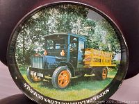 Front view showing colorful image of 1948 Packard delivery truck with yellow wood rails and orange wheels in natural outdoor setting, black round rim