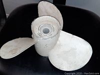 View of the boat propeller showing three aluminum blades and central hub with splines.