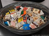 Top view showing a large roasting pan filled with diverse vintage advertising matchbooks.