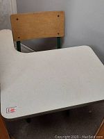 Photo showing beige laminate desktop surface with slight wear and small red price tag on corner.