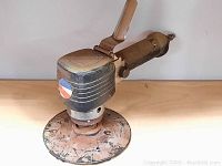 Front view of air tool buffer sander showing Pepsi Cola label and circular sanding pad with surface wear and rust.