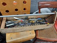 Wooden tool box filled with various hand tools such as screwdrivers, chisels, and knives