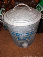 Front view of galvanized metal cylindrical cooler with lid and blue 'ARCTIC BOY' lettering.