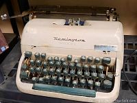 Photo of a vintage Remington typewriter showing teal keys and off-white body, with visible wear and some discoloration.