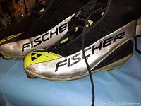 Side view of silver and yellow Fischer ski boot showing branding and laces.