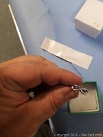 Silver infinity ring held in hand showing shape and size.