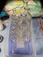 View of 11 clear glass vintage medicine bottles from above, showing their shapes and necks