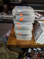 Stack of 28 DVDs in clear plastic cases with orange price stickers visible on the edges, placed on a wooden surface.