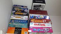 Photo of stacked board game boxes showing titles: Scene It?, Trivial Pursuit, Monopoly, Life, Friends Ultimate Trivia Game, Pictionary, Scrabble, Scattergories.