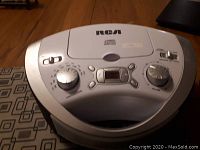 Top view of silver RCA CD player and radio combo device showing control knobs, buttons, and CD lid.
