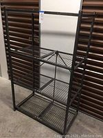 Full front view of the black Origami collapsible shelving unit showing all four wire shelves and frame.