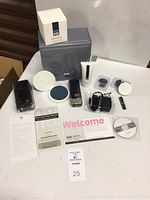 Full set of No No hair removal device and accessories on table including box, case, charger, moisturizer, guides, and welcome card.