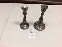 Two sterling silver weighted candlesticks displayed with auction lot number 35 visible on white surface