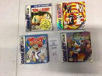 Four Game Boy Color game boxes: Tom and Jerry, Spy vs. Spy, Woody Woodpecker, and Goin' Quackers, showing front cover artwork and Nintendo/Game Boy Color branding.