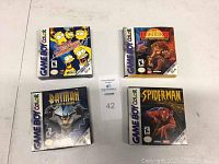 Four Game Boy Color games with original front covers showing titles The Simpsons, The Lion King, Batman, and Spider-Man.