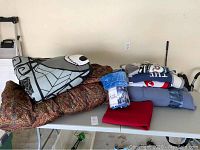 Full view of assorted comforters, blankets, and throws including Jack Skellington comforter and brown patterned quilt stacked on table.
