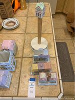 Top view of Lenox Village set showing several porcelain village house pieces arranged on counter, including salt and pepper shakers, napkin holder, and covered butter dish, with auction tag 79.