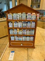 Frontal view of wooden rack fully loaded with 24 porcelain spice jars and visible bottom drawer knob