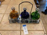 Front view of all three colored glass decanters in their metal tray
