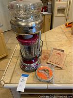 Front view of Margaritaville Frozen Concoction Maker with blending jar and assortment of manuals and coaster on kitchen counter.