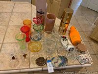 Full lot on tiled countertop including glassware, coasters, wine cooler, champagne container, and bottle holders.