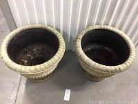 Top-down view of the two identical beige resin planters showing interior condition and design pattern.