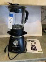 Cuisinart Blend and Cook Soupmaker with blending jar installed and instruction booklet next to it on countertop.