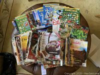Top view of a pile of Disneyana and Chocolatier magazines on a leather surface, showing colorful covers with Disney pins and chocolate desserts.