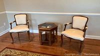 Two matching formal sitting chairs with wood trim placed in a room
