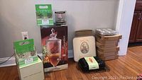 Beverage dispenser in box, multiple boxes of baking tins and NordicWare pan, set of pint glasses and wrapped black item