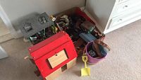 Photo of wooden toy barn with red roof showing toy animals inside and plastic bucket with shovel outside
