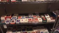 Wide view of multiple Hallmark Keepsake Ornament boxes arranged on metal shelving, showing various holiday-themed ornaments in original packaging.