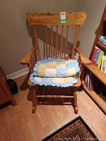 Front view of wooden rocking chair with folded patchwork seat cushion placed on seat.
