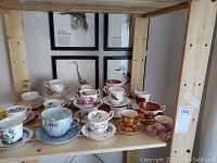 Wide shelf display of assortment of bone china tea cups and saucers