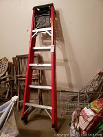Red 6 foot step ladder standing upright showing full height and aluminum steps.