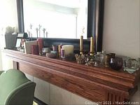 Wooden mantle with assorted candles, candle holders, and picture frames arranged on top.