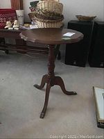 Full view of the vintage wooden cricket table showing claw feet and scalloped table top.
