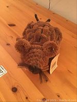 Photo of the 100% coconut fiber mouse-shaped boot scraper on a wooden surface showing the front side with tag and detailed coiled fiber texture.