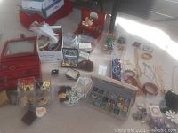 Wide view of assortment of costume jewelry including boxes, bracelets, necklaces, rings, earrings, and hair clips laid out on table.