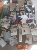 Wide view of assorted costume jewelry including brooches, rings, earrings, and necklaces spread on a flat surface with some jewelry boxes.