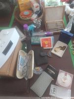 View of assorted personal care items including perfume bottles, wallet, nail trimmers, key box, and small radio on a table.
